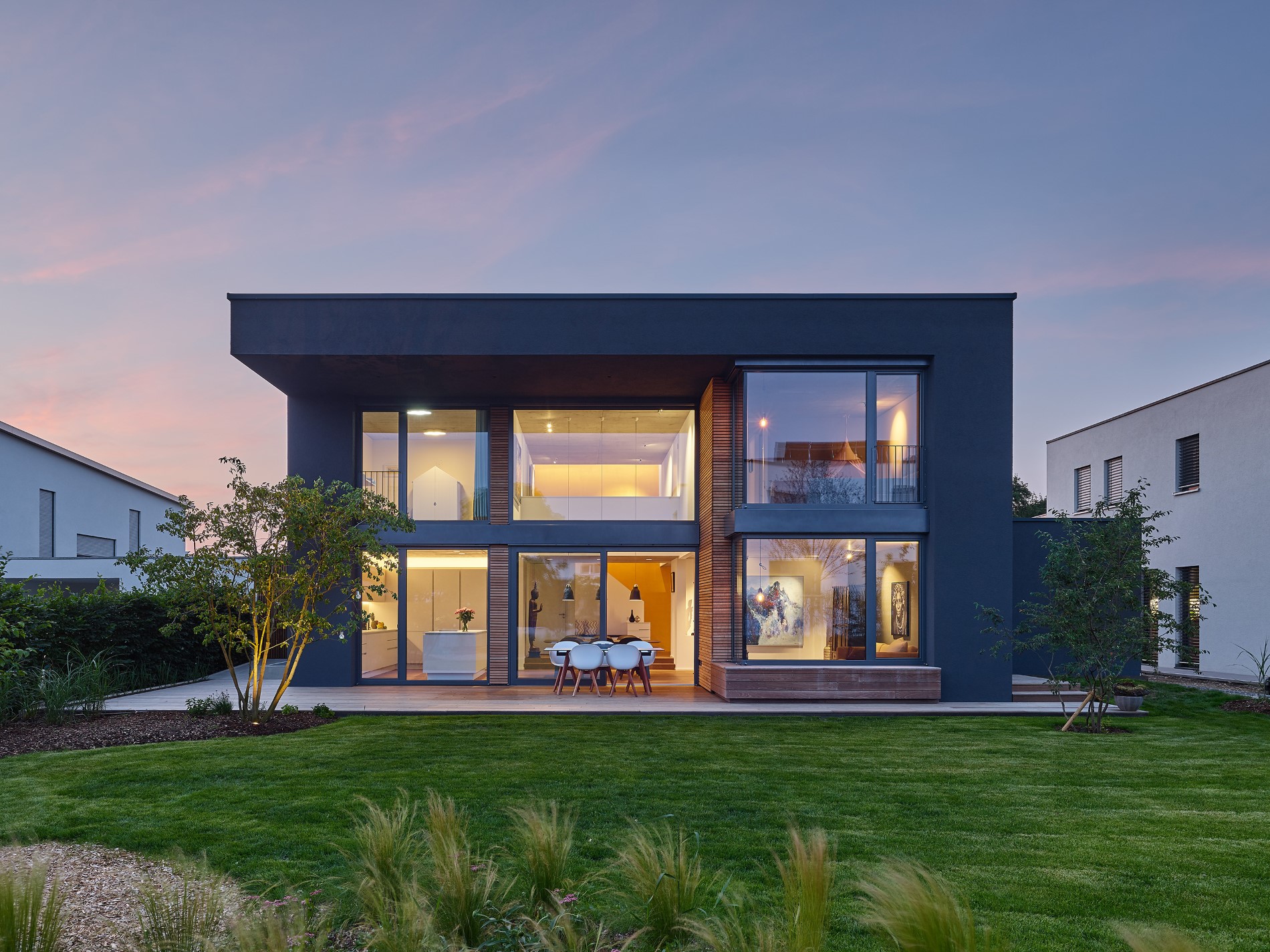 Einfamilienhaus mit großer Glasfront in der Abenddämmerung