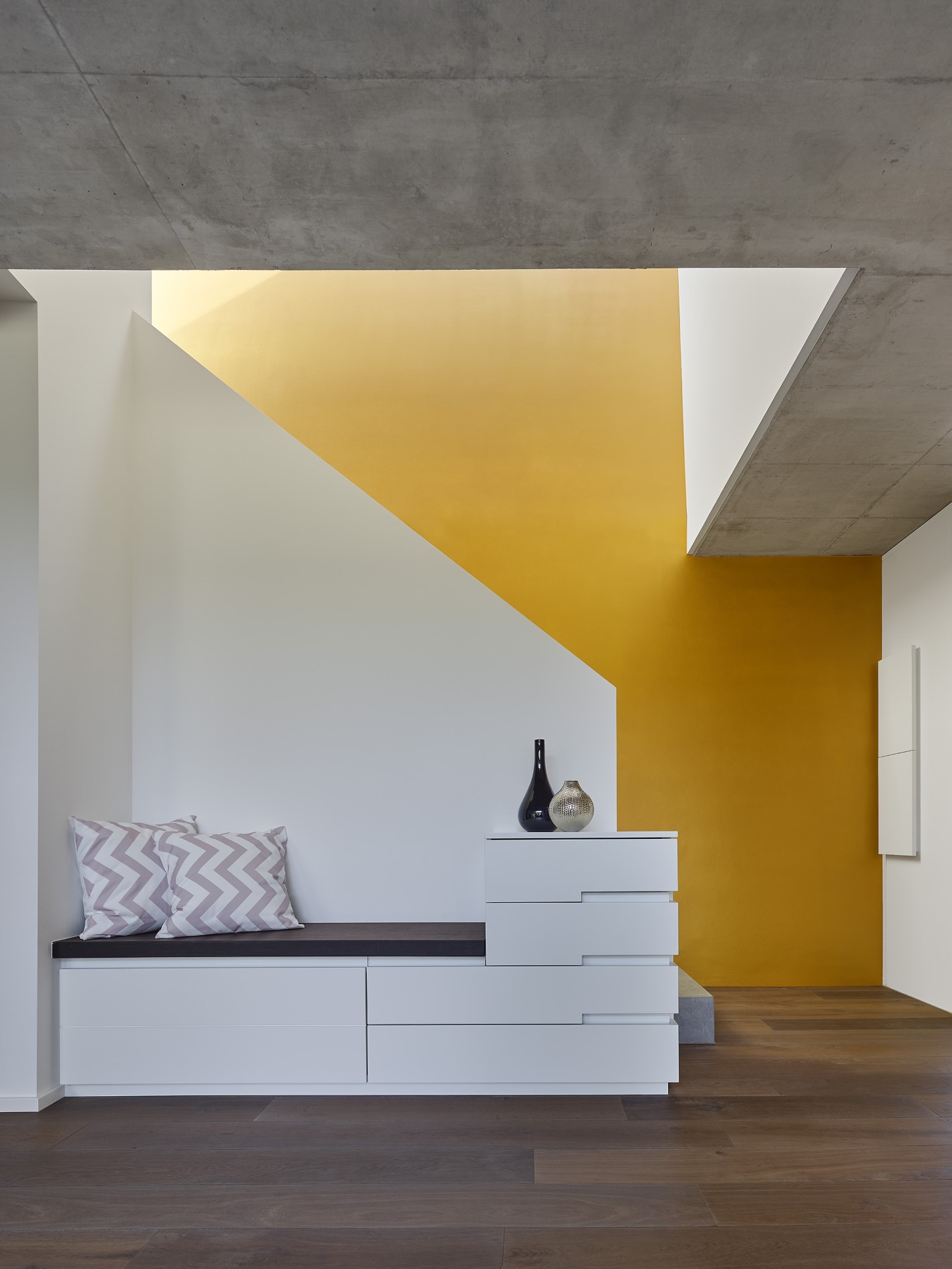 Sitznische mit gelber Wand unter der Treppe